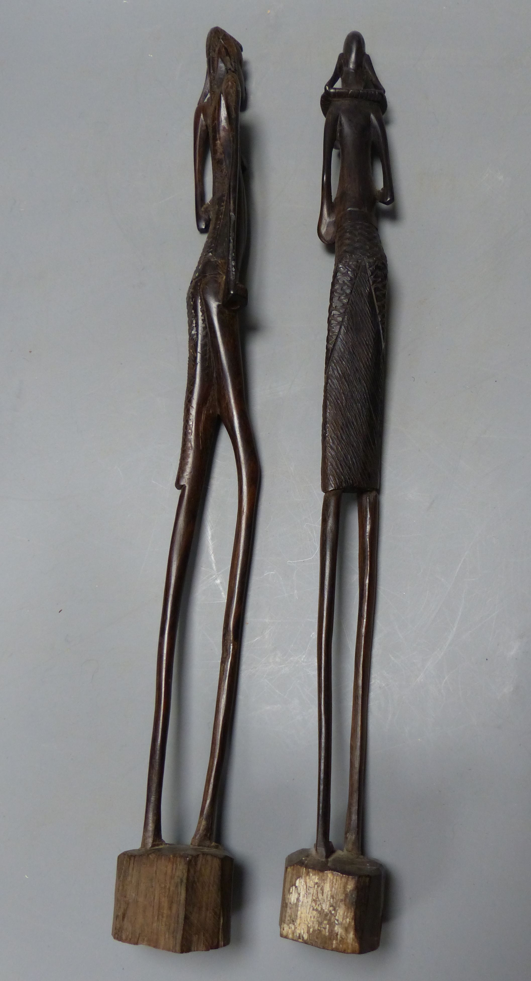 A pair of ebony African sculptures and a carved baton, longest 56cm